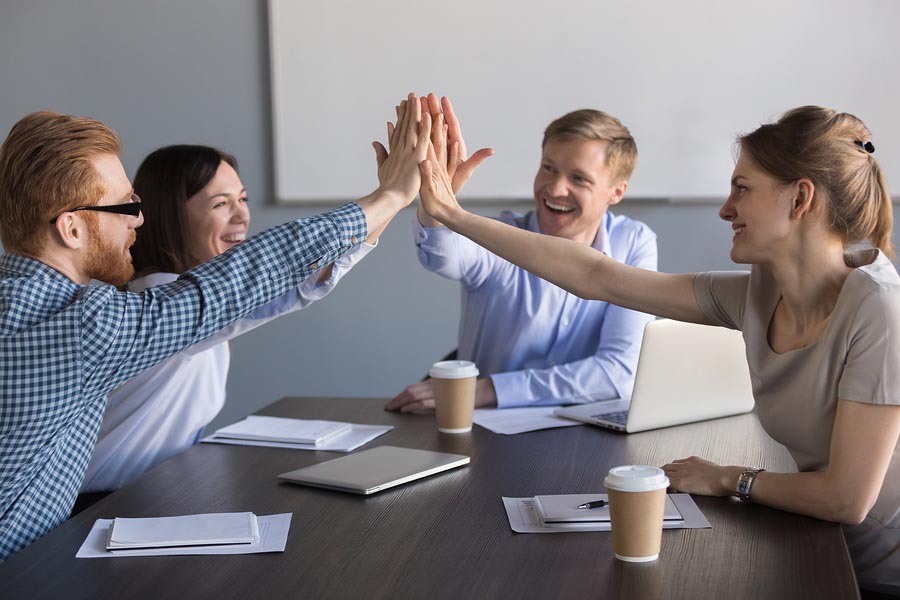 Excited Business Team Of Employees Giving High Five During Meeti